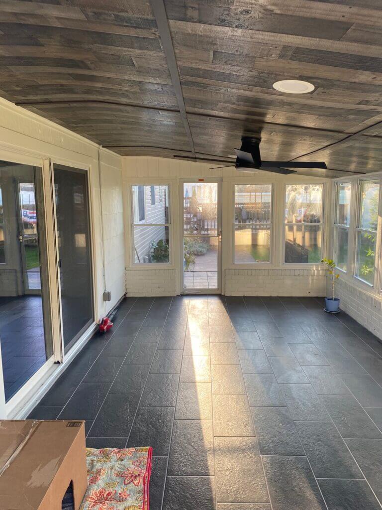 Sunroom interior with slate-look tile floor and a wood plank ceiling