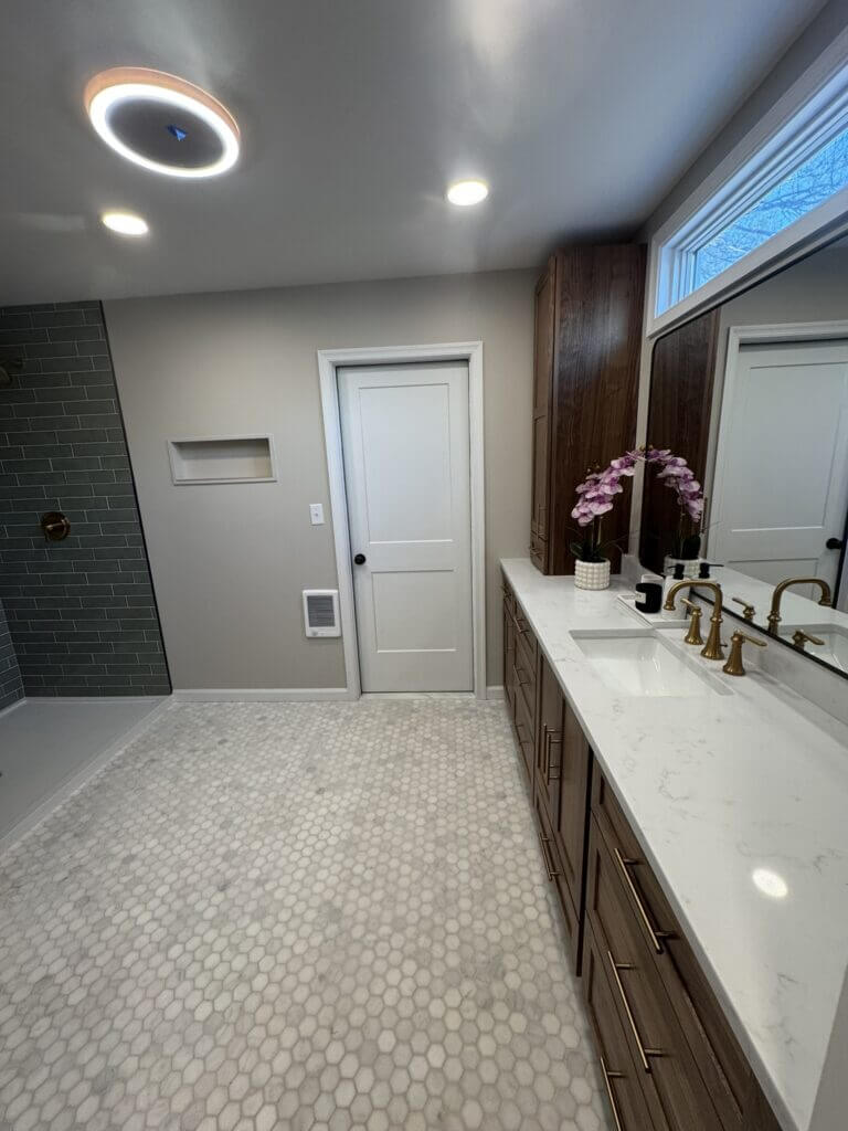 Primary bathroom with a long dark wood vanity, transom window and hex tile floor