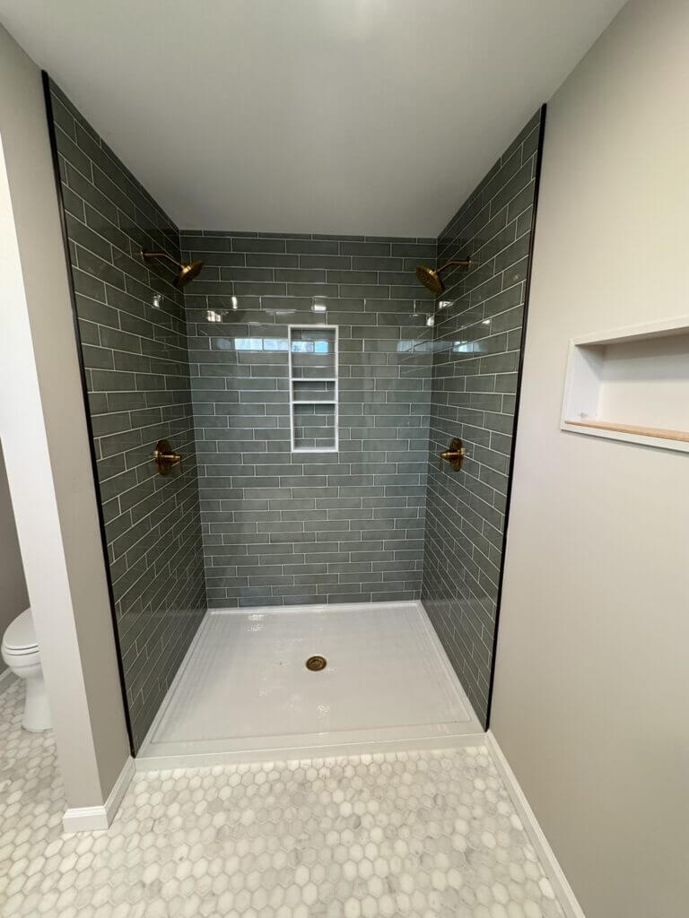 Walk-in shower with green subway tile, a built-in niche and a low threshold