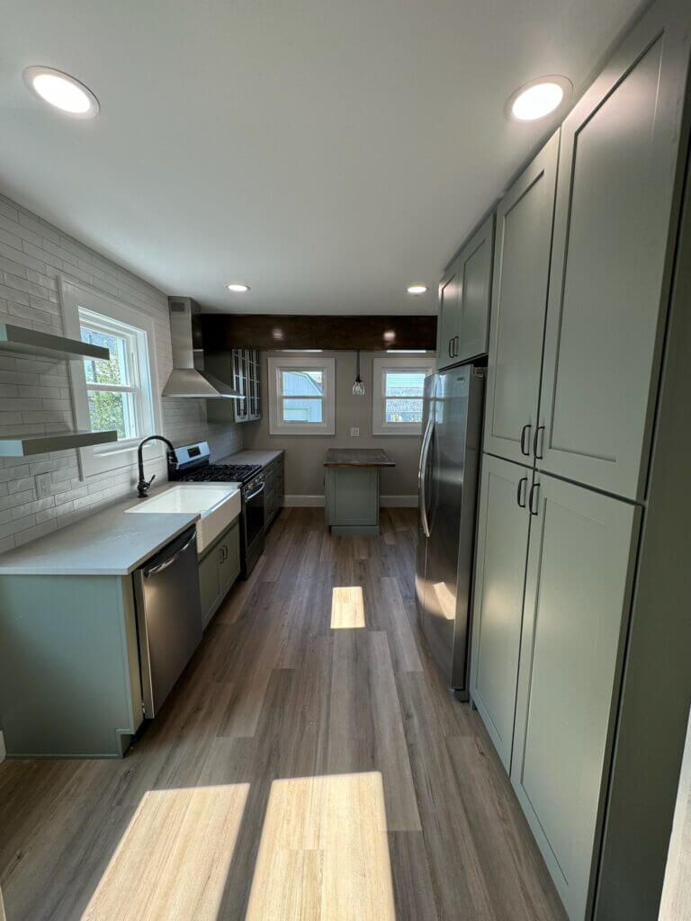 Galley kitchen remodel with sage green cabinets and wood-look plank flooring