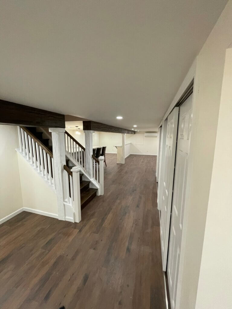 Finished basement with a painted staircase, railing and plank flooring