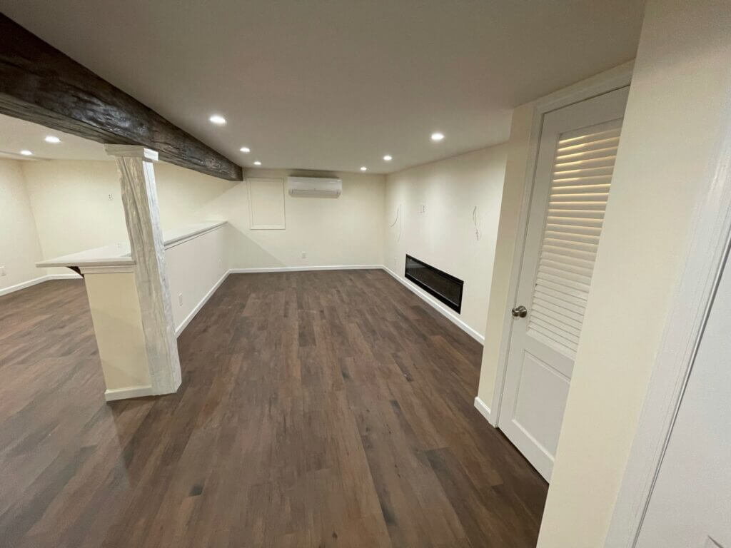 Finished basement with an exposed beam, finished column and plank flooring