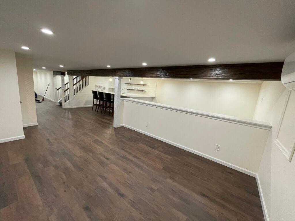 Finished basement with a bar, half wall and staircase to the main floor