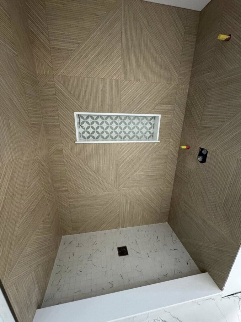 Walk-in shower with warm wood-look tile and a decorative mosaic niche