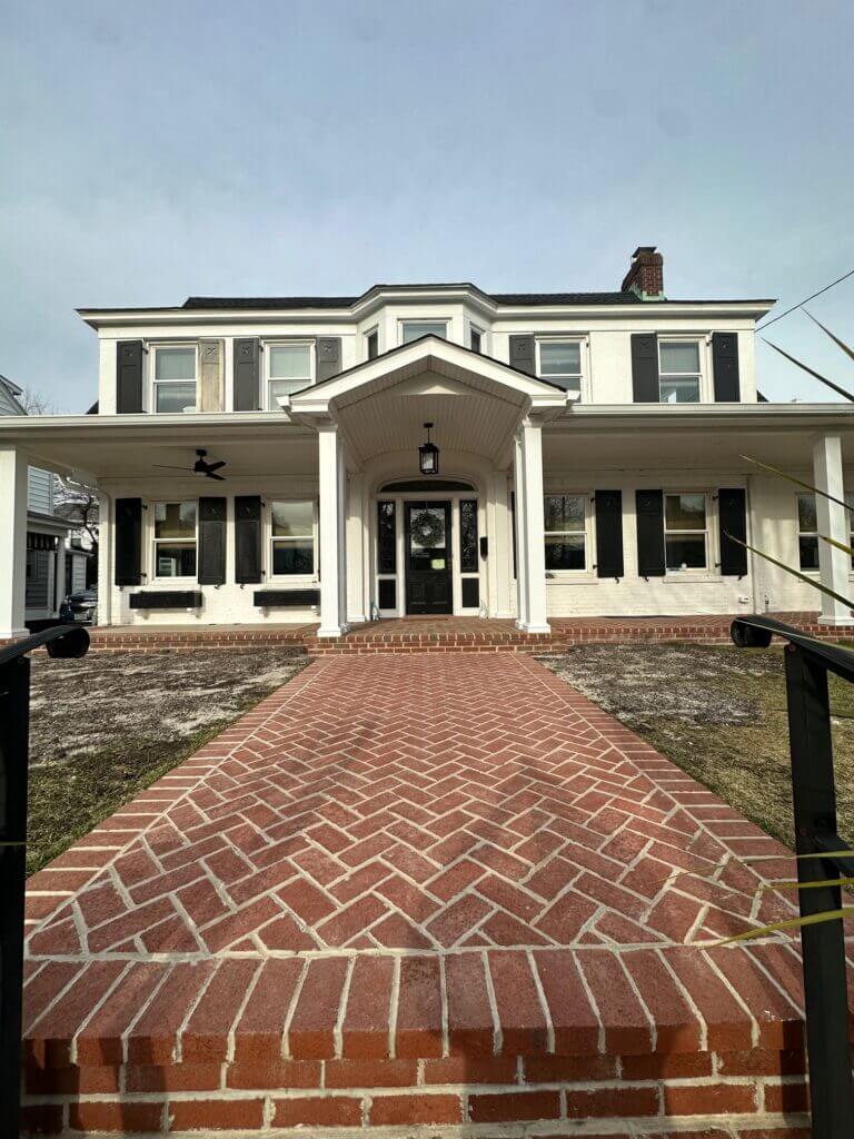 White colonial with a columned portico and a herringbone brick walkway