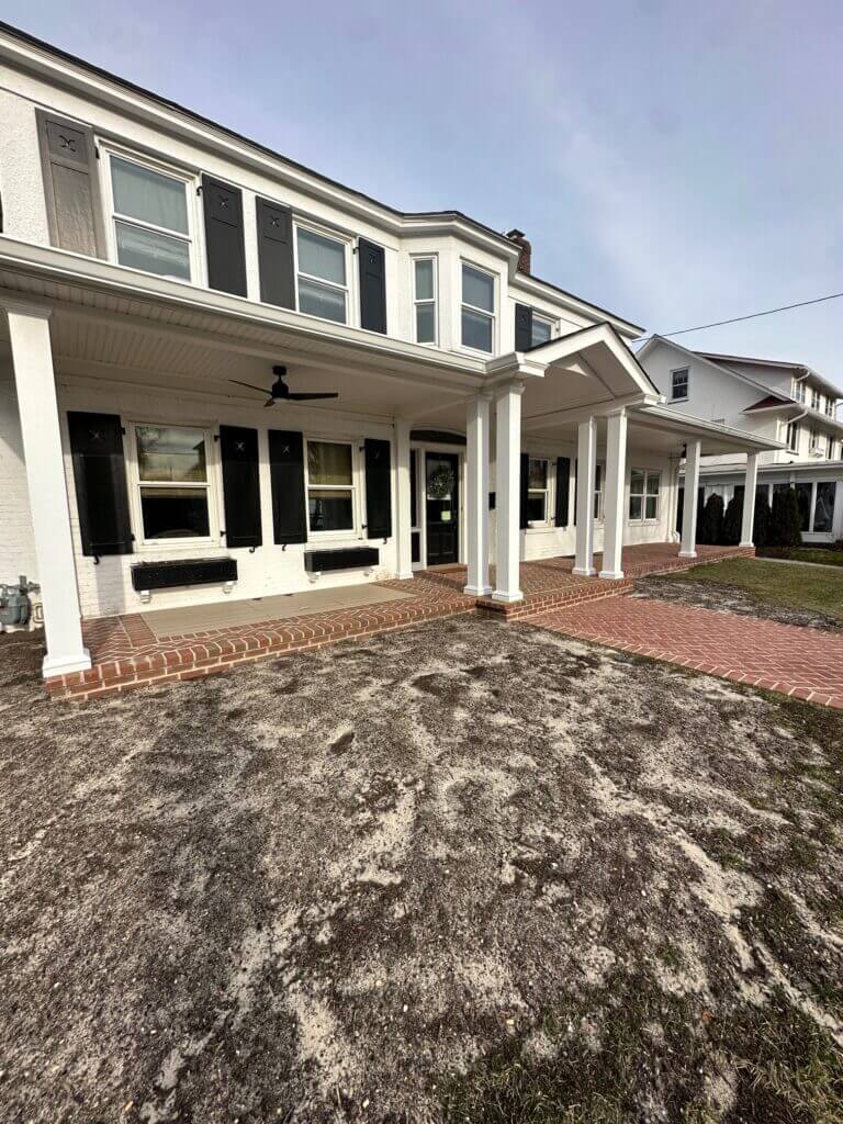 Colonial home with a covered front porch and a brick patio and walkway