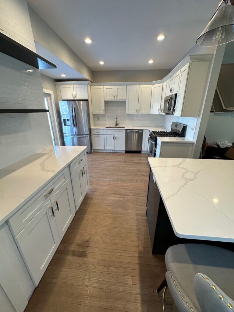 White kitchen remodel with a waterfall quartz counter and stainless appliances