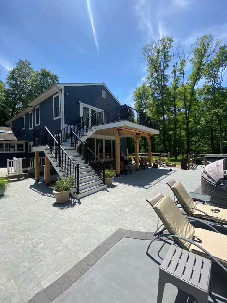 Modern two-story home with a timber-framed covered patio and paver decking
