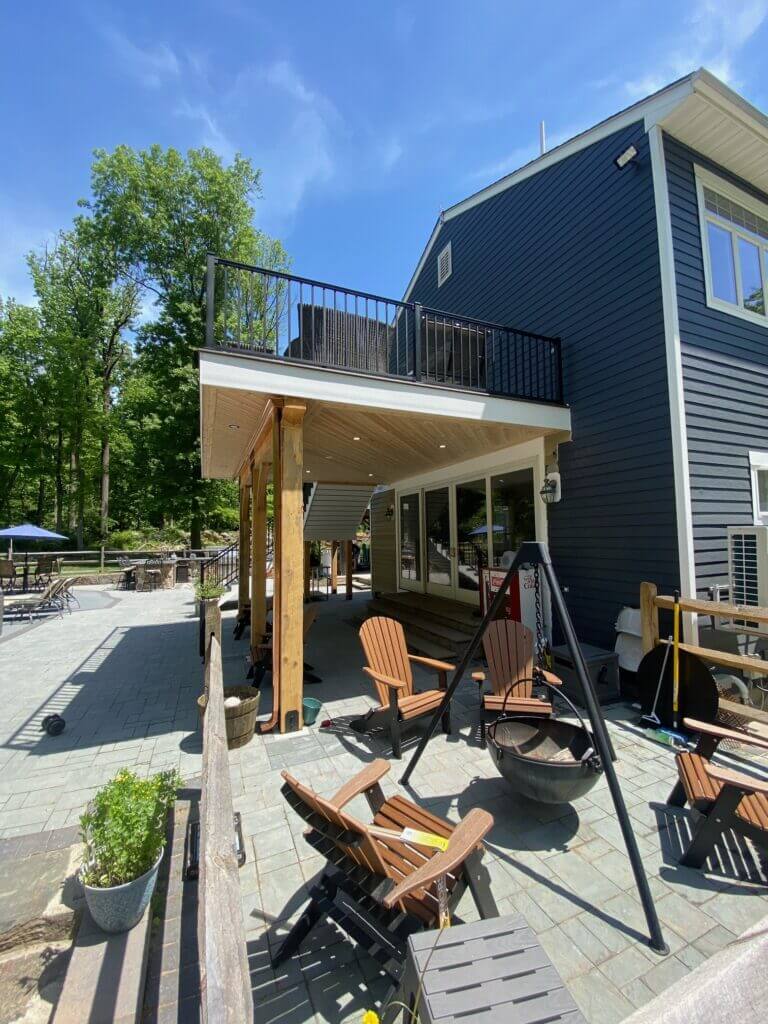 Timber-framed covered patio beneath a raised deck with a paver floor