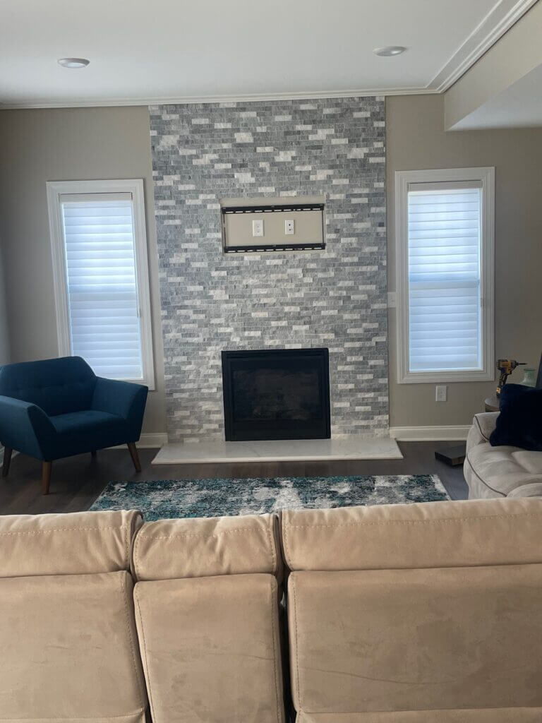 Living room with a stone tile fireplace surround and shuttered windows