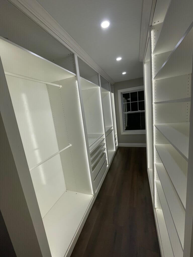 Custom walk-in closet with white built-in shelving and plank flooring