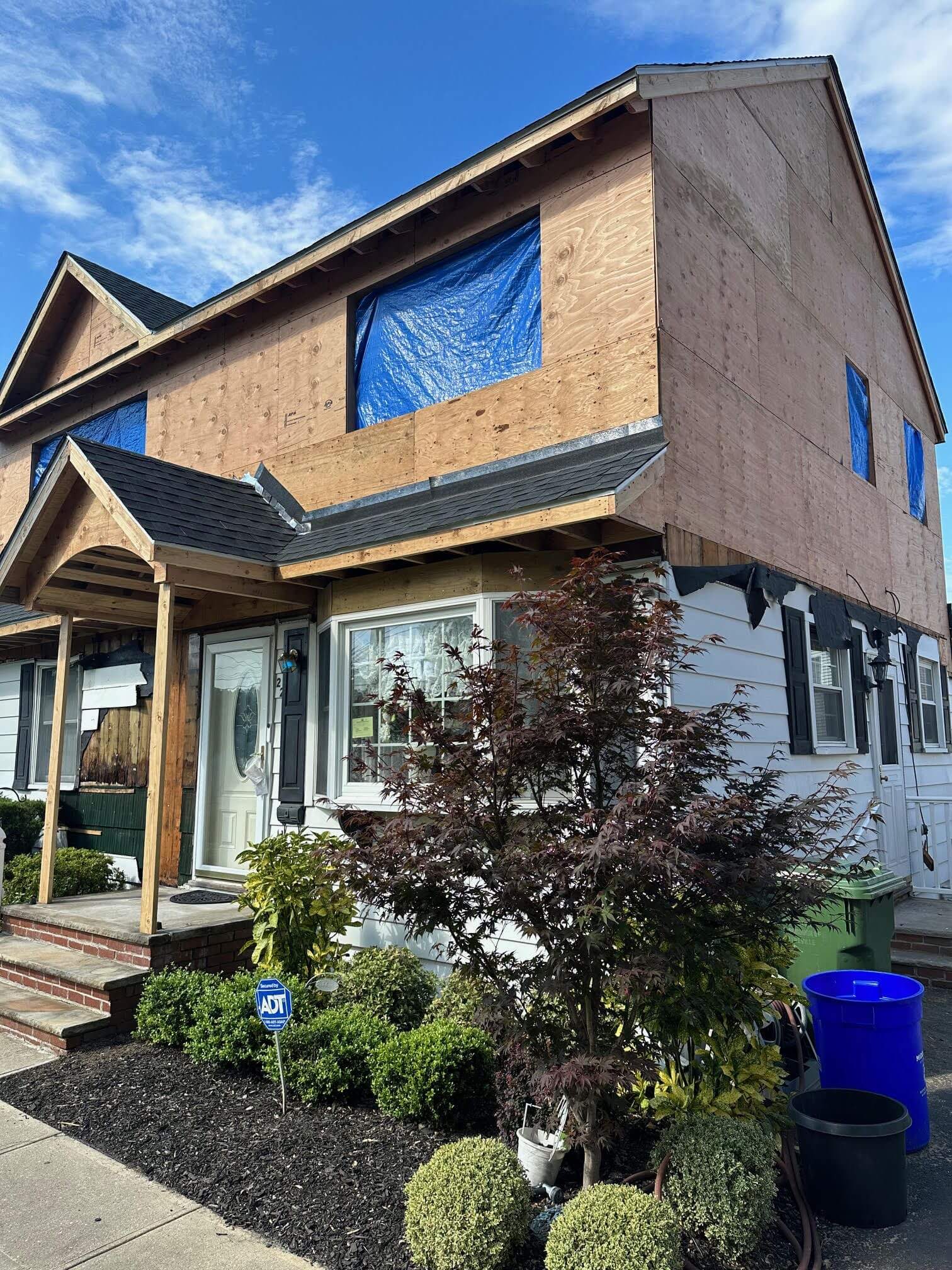 Home addition construction progress with blue tarps and exposed framing during second story build in Middlesex County NJ