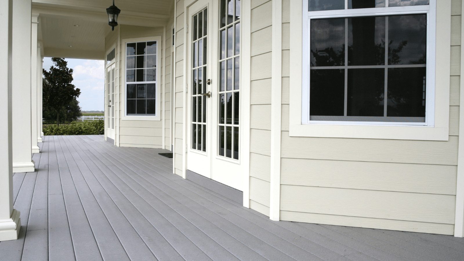 Covered porch along the side of a New Jersey home with grey decking and French doors