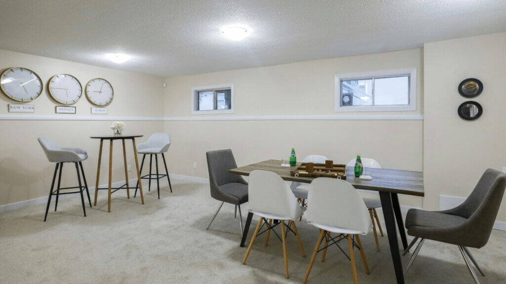 Finished basement with a bar-height table, counter stools and a dining area