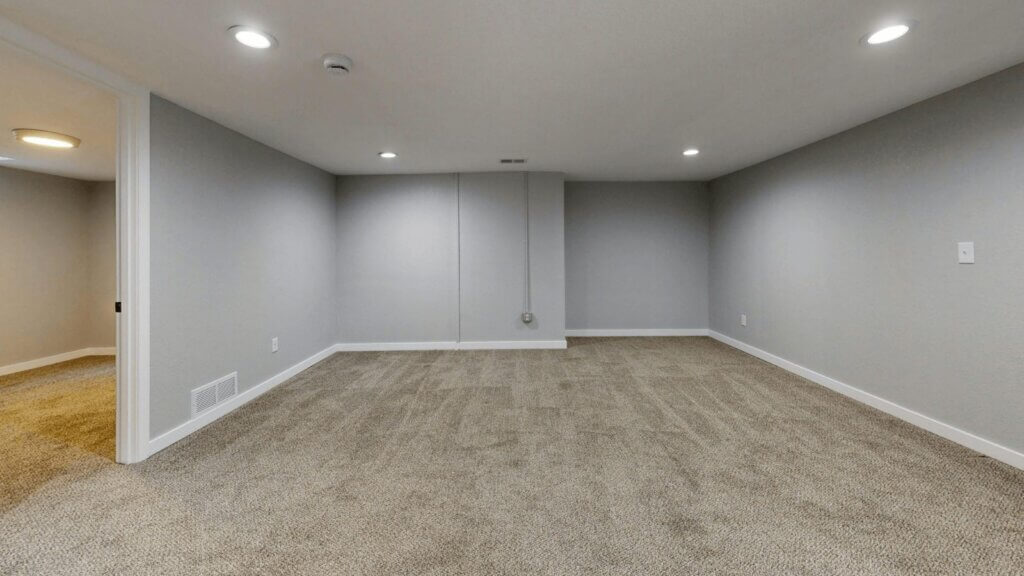 Finished basement family room with fresh drywall, carpet and recessed lighting