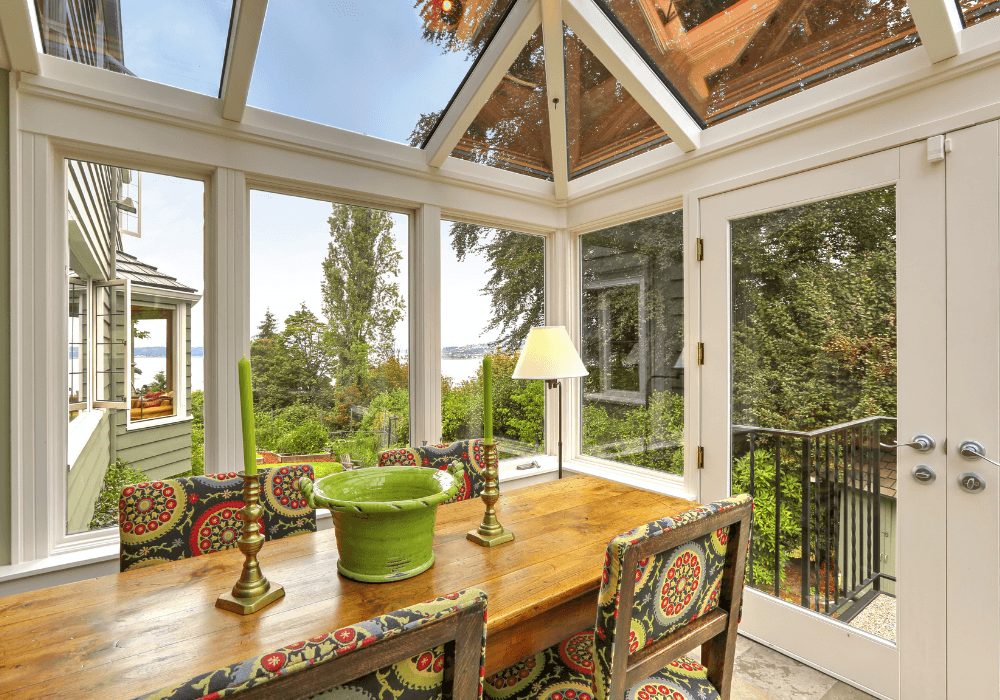 Sunroom dining nook with a wooden table, patterned chairs and a table lamp