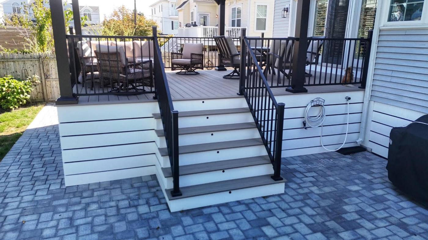 Custom composite deck with black railing behind a New Jersey home