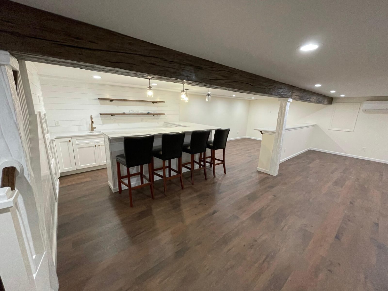 Finished basement with a bar, counter seating and an exposed beam
