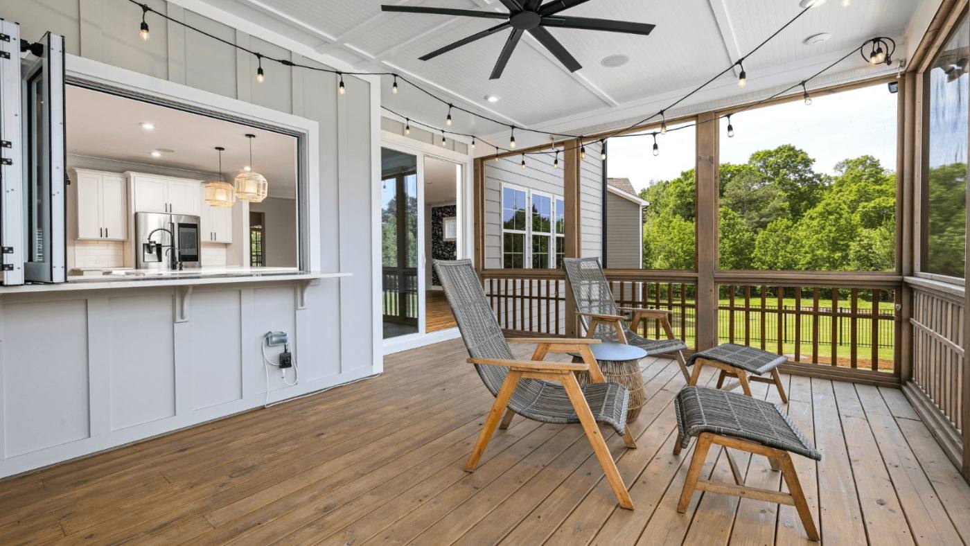 Screened porch with a kitchen pass-through window, ceiling fan and string lights